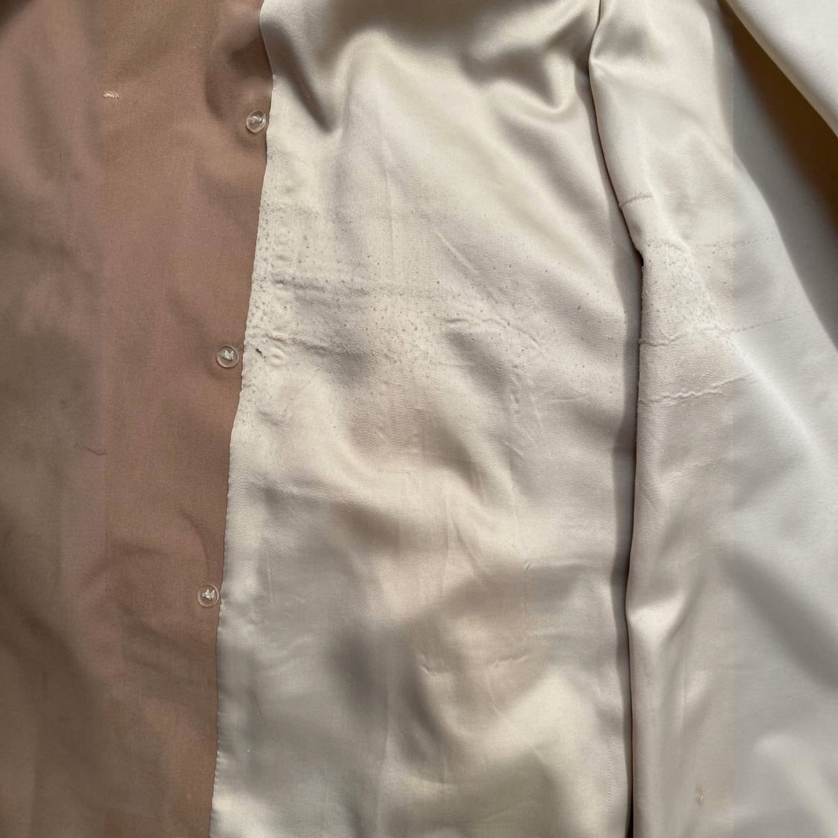 Detalle del forro interior de satén beige en una gabardina Bruno Corza